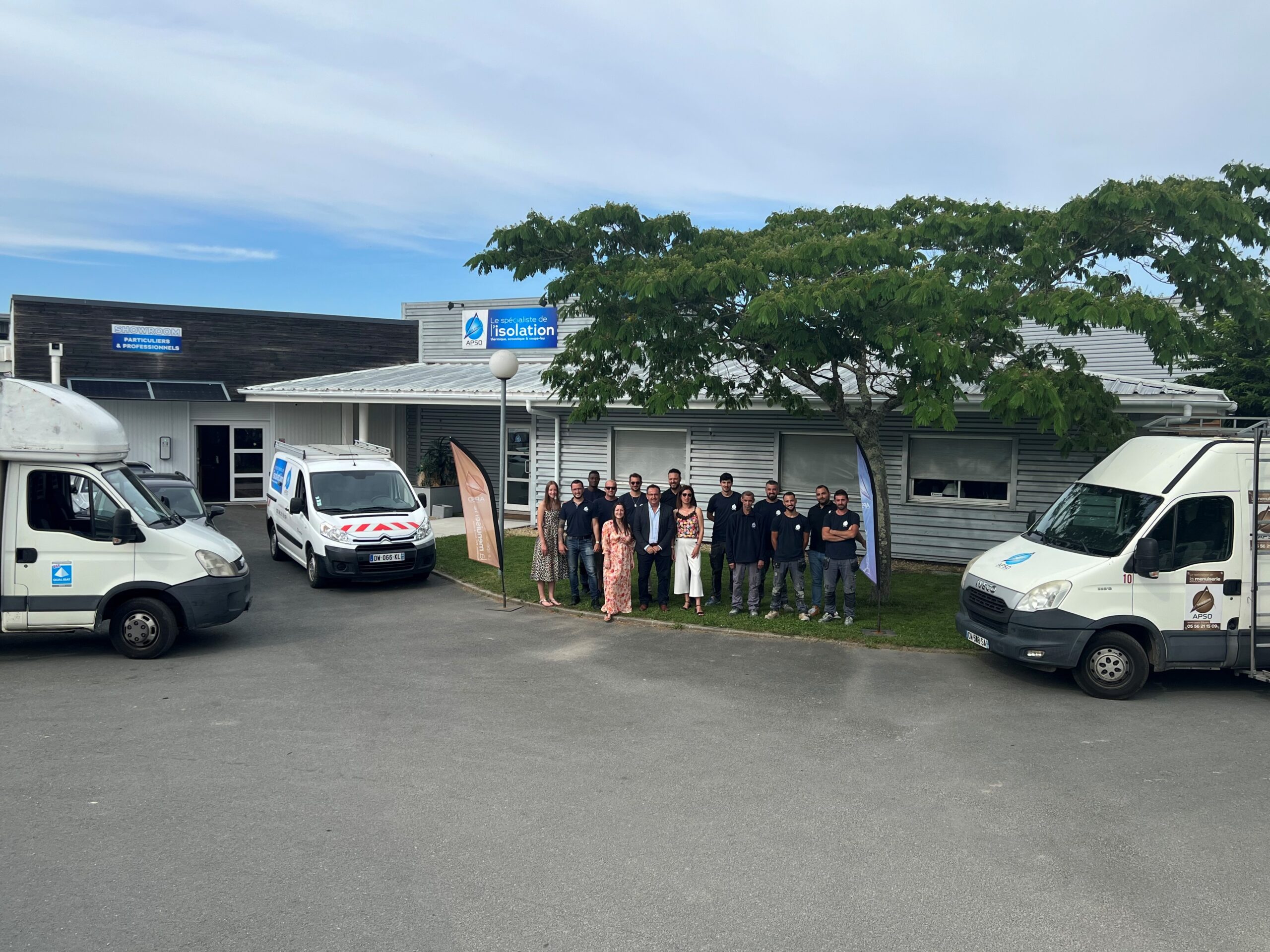 Équipe APSO devant le showroom "Le spécialiste de l'isolation" avec ses fourgonnettes d'intervention professionnelles.