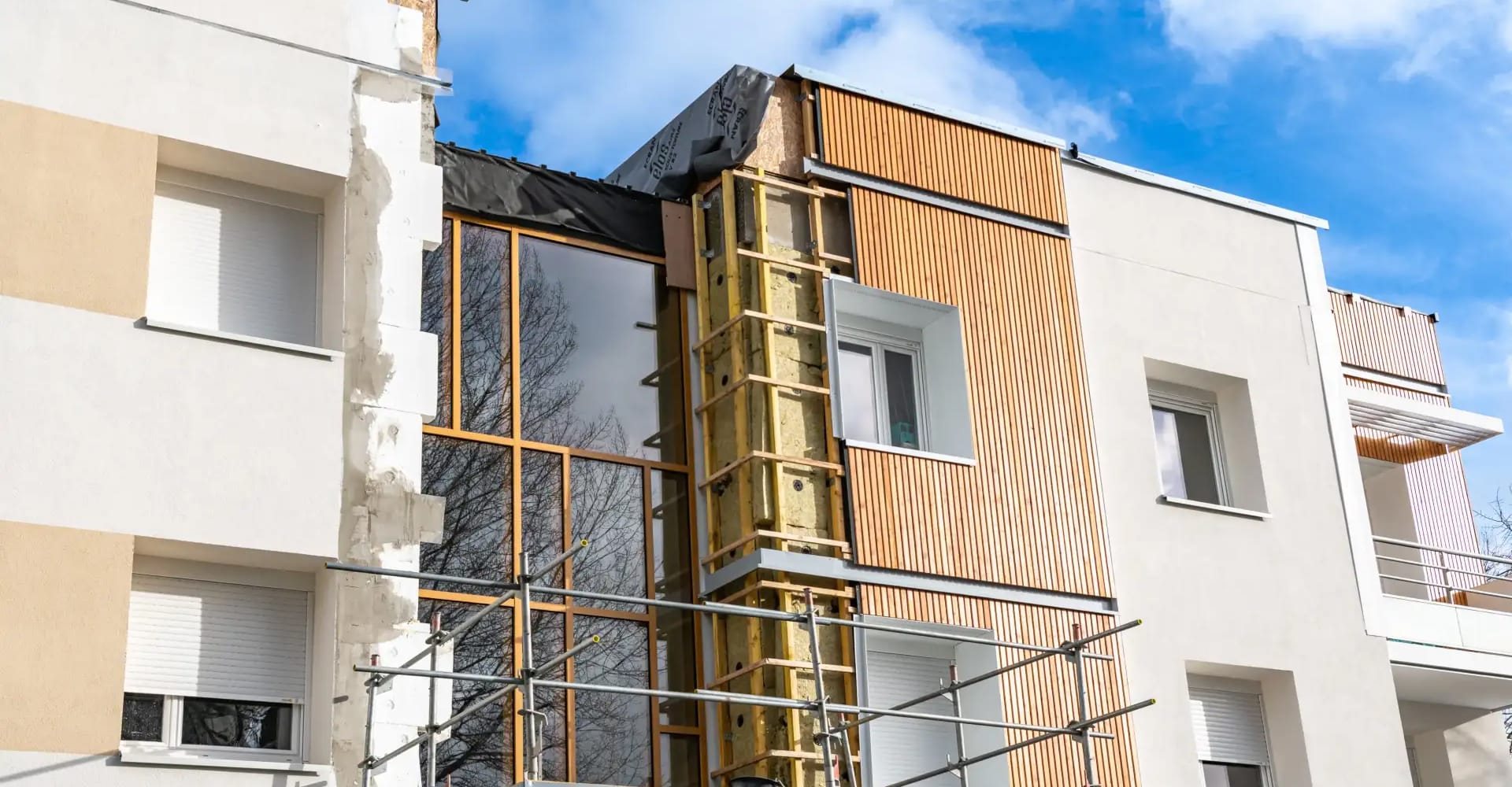 Rénovation de façade d'un immeuble avec isolation thermique par l'extérieur et bardage bois décoratif.